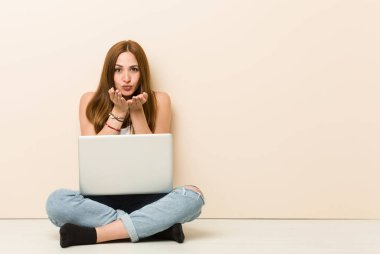 Genç zencefil kadın evinin zemin katlanır dudakları oturan ve hava öpücük göndermek için avuç içi tutarak.