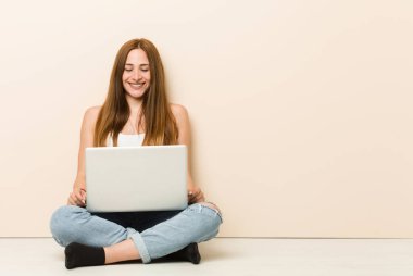 Genç zencefil kadın evinin katta oturan güler ve gözleri kapatır, rahat ve mutlu hissediyor.