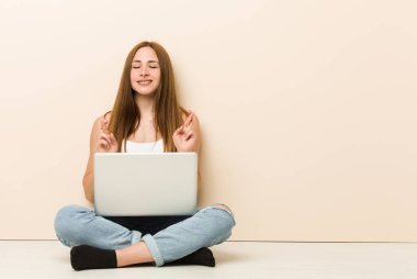 Genç zencefil kadın şans için parmaklarını geçiş evinin zeminüzerinde oturan