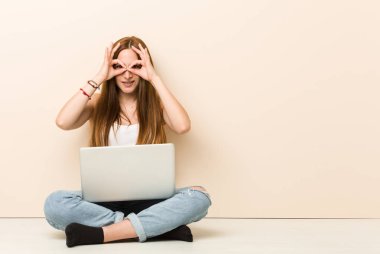 Genç zencefil kadın gözlerinin üzerinde tamam işareti gösteren evinin zeminüzerinde oturan