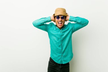 Çok yüksek ses duymamaya çalışan elleri ile kulakları kapsayan bir yazlık giysiler giyen genç İspanyol adam.