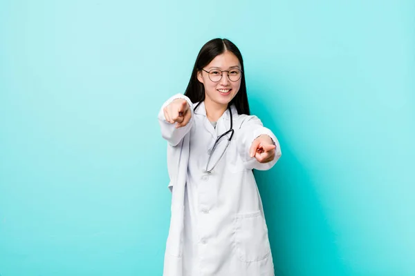 Young chinese doctor woman cheerful smiles pointing to front.