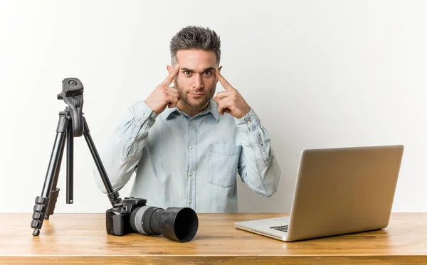 Young handsome photography teacher focused on a task, keeping forefingers pointing head.