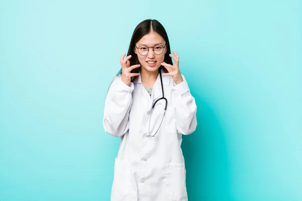 Young chinese doctor woman upset screaming with tense hands.