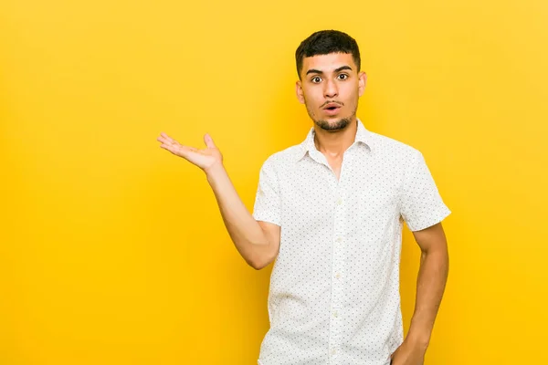 Young Hispanic Man Impressed Holding Copy Space Palm — Stock Photo, Image