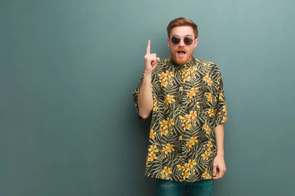 Young redhead man wearing exotic summer clothes having an idea, inspiration concept