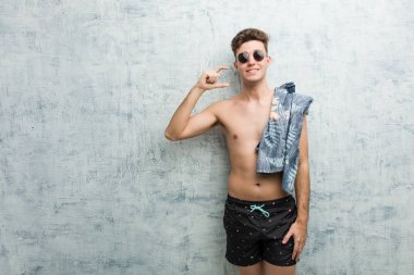 Ön parmakları yla küçük bir şey tutan, gülümseyen ve kendinden emin bir şey tutan bir mayo giyen genç adam.