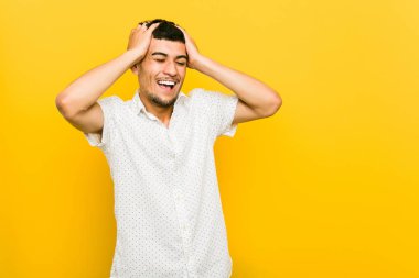 Genç İspanyol adam sevinçle başını ellerini tutarak gülüyor. Mutluluk kavramı.