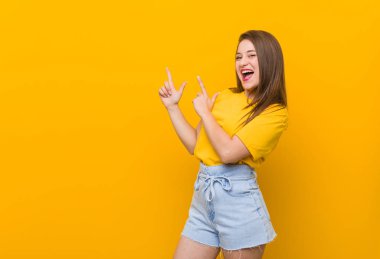 Bir fotokopi alanı için ön parmakları ile işaret eden sarı bir gömlek giyen genç kadın genç, heyecan ve arzu ifade.