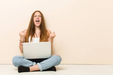 Genç zencefil kadın evinin zemininde kaygısız ve heyecanlı tezahürat oturuyor. Zafer kavramı.