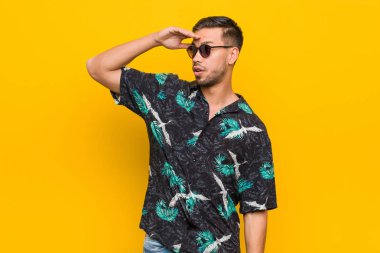 Genç filipinli adam yaz giysileri giyen uzak alnında el tutmak görünümlü.