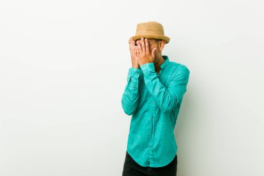 Yazlık kıyafetler giyen genç İspanyol adam korkmuş ve gergin parmaklarıyla göz kırpıyor.