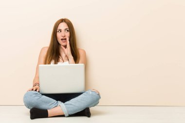 Evinin zemininde oturan genç zencefilli kadın gizli bir sıcak frenleme haber söylüyor ve kenara bakıyor