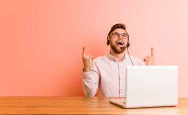 Çağrı merkezinde çalışan genç adam, her iki ön parmağıyla boş bir boşluk gösterirken gösterir.