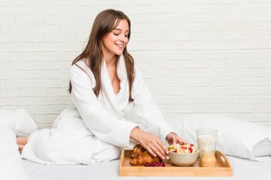 Genç beyaz kadın kahvaltı yapıyor.