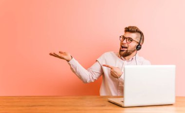 Bir çağrı merkezinde çalışan genç adam avuç içinde bir kopya alanı tutarak heyecanlı.