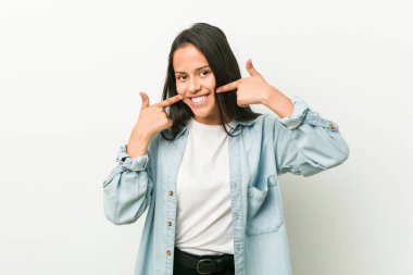 Genç İspanyol kadın gülümsüyor, ağzına parmaklar işaret.