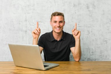 Bir masa üzerinde dizüstü bilgisayarı ile çalışan genç girişimci boş bir boşluk gösteren kadar her iki ön parmak ile gösterir.