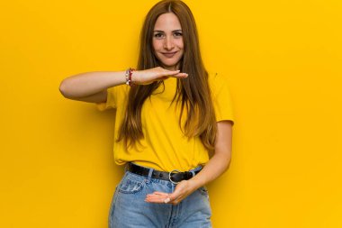 Genç zencefil kızıl saçlı kadın iki eliyle bir şey tutarak, ürün sunumu.