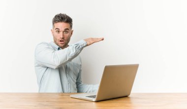 Onun laptop ile çalışan genç yakışıklı adam şok ve eller arasında bir kopya boşluk tutarak hayran.