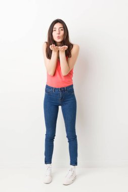 Beyaz arka plan katlanır dudaklar üzerinde tam vücut genç kadın ve hava öpücük göndermek için avuç tutan.