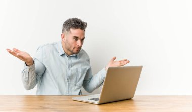 Onun laptop ile çalışan genç yakışıklı adam silah ile ölçek yapar, mutlu ve emin hissediyor.