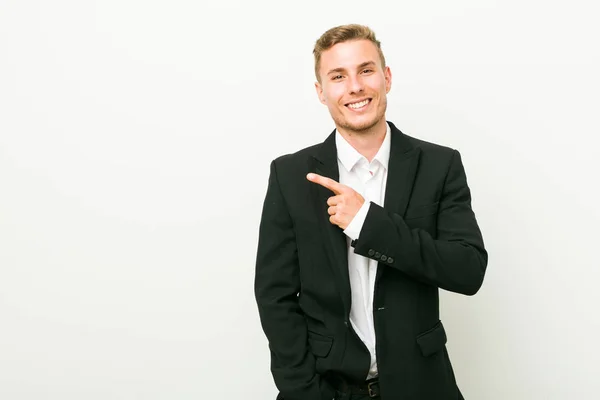 若い白人男性ビジネスマンは微笑み 脇を指差し 空白のスペースで何かを示す — ストック写真