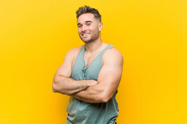 年轻的健身男子在黄色的背景微笑自信与交叉的手臂 — 图库照片