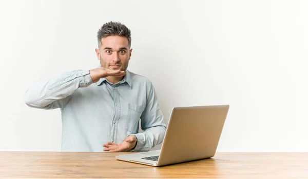 Jovem Homem Bonito Trabalhando Com Seu Laptop Segurando Algo Com — Fotografia de Stock