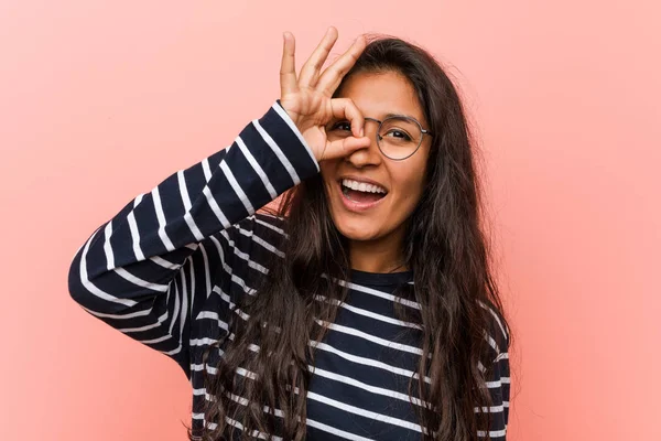 Young intellectual indian woman excited keeping ok gesture on eye.