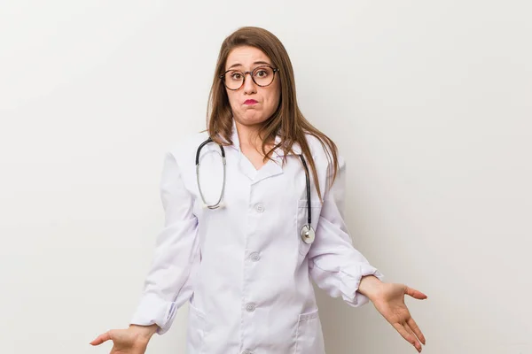 Jonge Dokter Vrouw Tegen Een Witte Muur Shrugs Schouders Open — Stockfoto