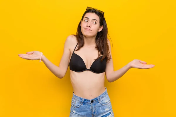 Młoda Brunetka Kobieta Ubrana Bikini Przeciwko Żółtym Tle Wątpie Wzruszając — Zdjęcie stockowe
