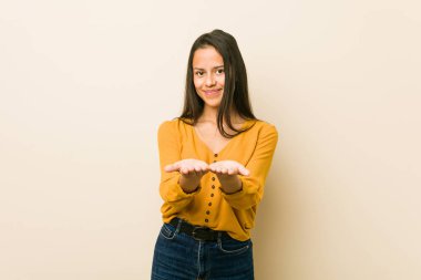 Küçük İspanyol kadın bir bej arka plan ile avuç içi bir şey tutarak, kamera sunan.