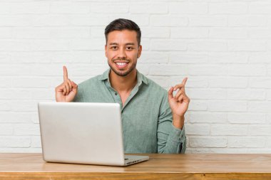 Onun laptop ile çalışan genç Filipinli adam boş bir alan gösteren her iki ön parmaklar ile gösterir.