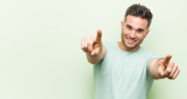 Yeşil bir arka plan neşeli karşı genç yakışıklı adam ön işaret gülümsüyor.