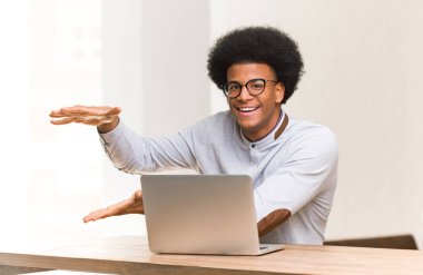 Genç siyah adam çok şaşırttı ve şok bir şey tutan dizüstü bilgisayarını kullanarak