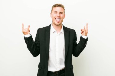 Genç beyaz iş adamı parmaklarıyla kaya jesti gösteriyor