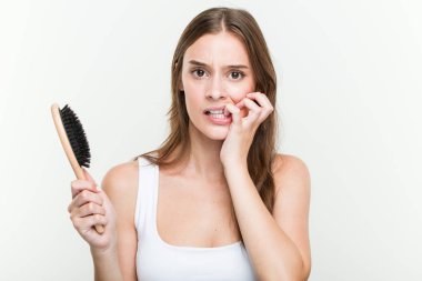 Genç beyaz kadın tırnakları ısırma bir saç fırçası tutan, sinirli ve çok endişeli.