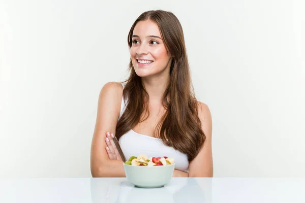 若い白人女性は クロスアームで自信を持って笑顔のフルーツボウルを食べる — ストック写真