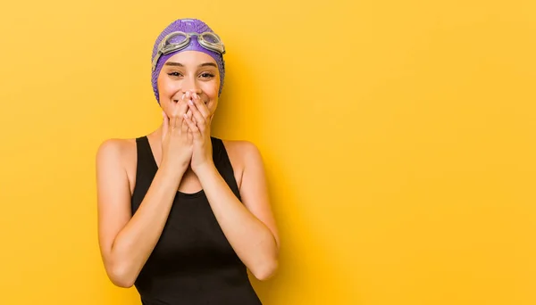 Young swimmer caucasian woman laughing about something, covering mouth with hands.