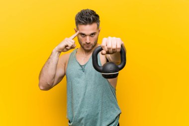 Kafkas adam parmağıyla tapınağını işaret eden bir bumbbell tutan, düşünce, bir görev üzerinde duruldu.