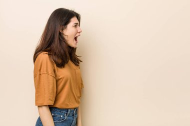 Bir kopya alanı doğru bağırarak bej arka plan karşı genç esmer kadın