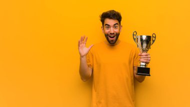 Bir zafer ya da başarı kutlayan bir kupa tutan genç adam