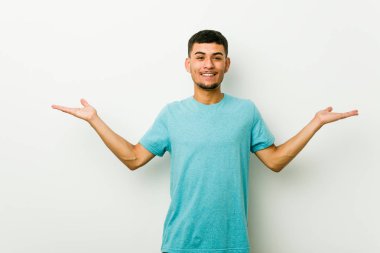 Genç İspanyol adam kolları ile ölçek yapar, mutlu ve kendinden emin hissediyor.