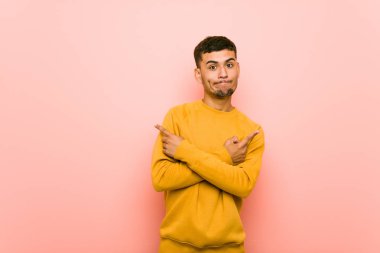 Genç İspanyol adam yan noktalar, iki seçenek arasında seçim yapmaya çalışıyor.