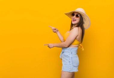 Hasır şapka takan genç beyaz kadın, yaz ait parmaklarla heyecanlı görünüyor.