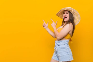 Hasır şapka takan genç beyaz kadın, yaz görünümünde bir fotokopi alanı nın işaretleriyle işaret ediyor, heyecan ve arzularını ifade ediyor..