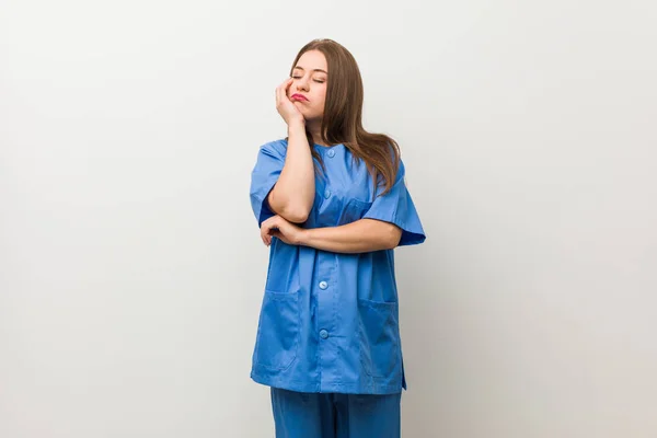 Jonge Verpleegster Vrouw Tegen Een Witte Muur Die Zich Verveelt — Stockfoto