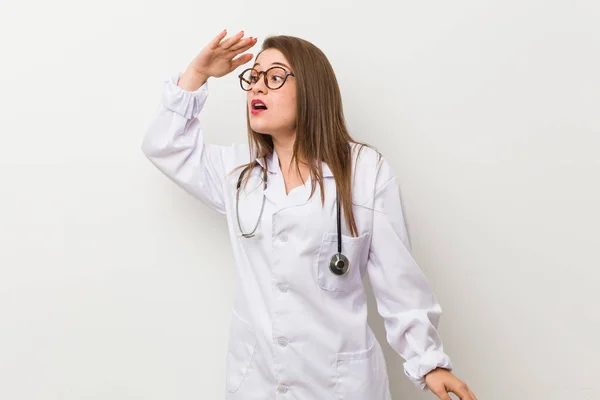 Jonge Dokter Vrouw Tegen Een Witte Muur Zoek Ver Weg — Stockfoto