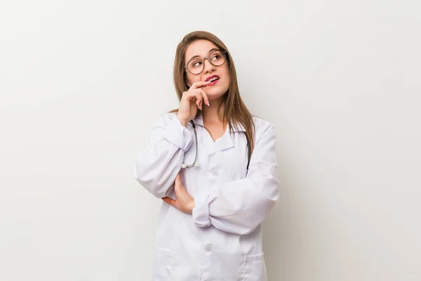 Giovane Donna Medico Contro Muro Bianco Rilassato Pensando Qualcosa Guardando — Foto Stock